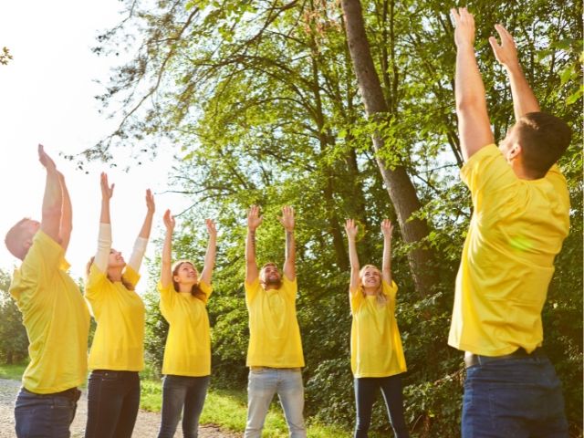 група с жълти тениски прави гимнастика на открито - снимка