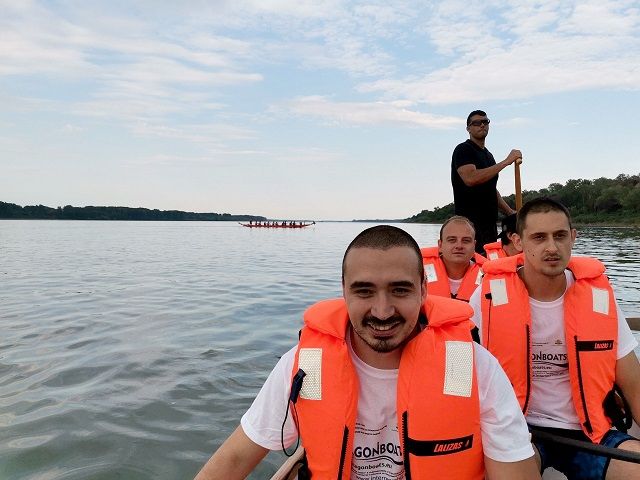 мъже със спасителни жилетки в драковони лодки 