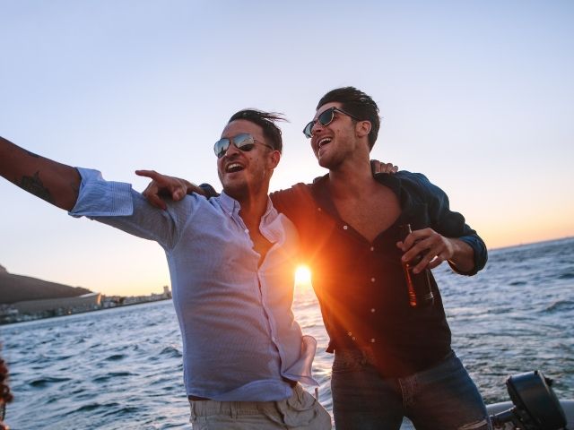 двама мъже в добро настроение на яхта на фона на залез слънце - снимка