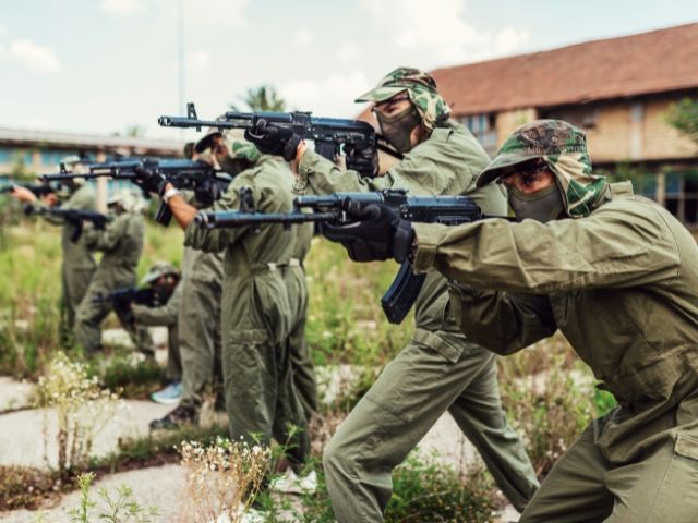 група мъже във военно облекло насочват оръжие - снимка