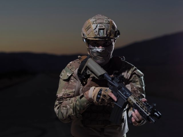 мъж в бойна екипировка с реплика за оръжие - снимка