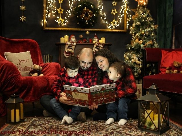 семейство с две деца, облечени в карирани ризи, четат коледна книжка