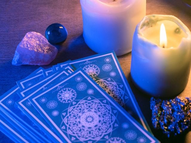 карти таро, кристали и запалени свещи на маса - снимка
