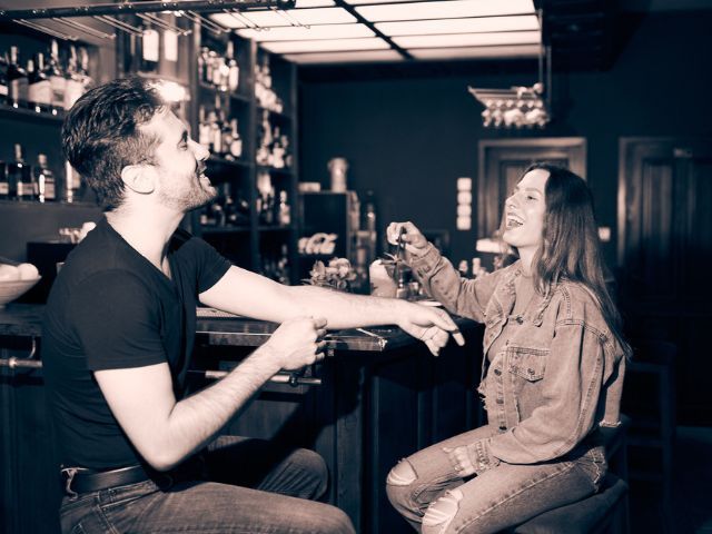 черно бяла снимка на мъж и жена, които седят в бар и се смеят