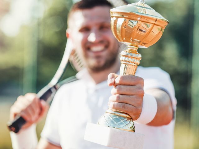 мъж държи купа от тенис турнир -снимка