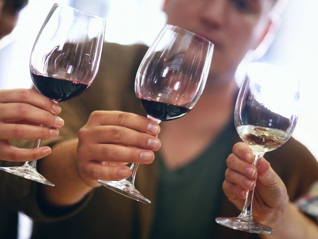 Хора държат чаши с червено и бяло вино