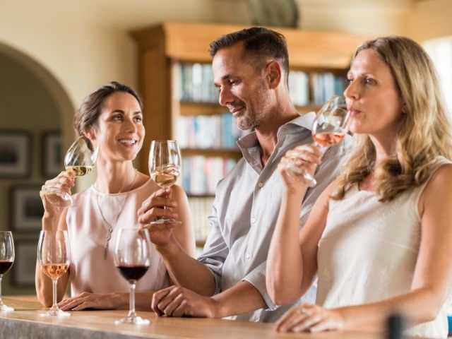две жени и един мъж пият вино