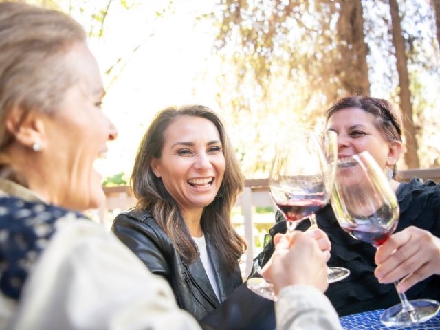 Три жени се смеят и пият вино