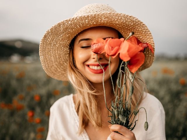жена държи букет от диви цветя и се усмихва - снимка
