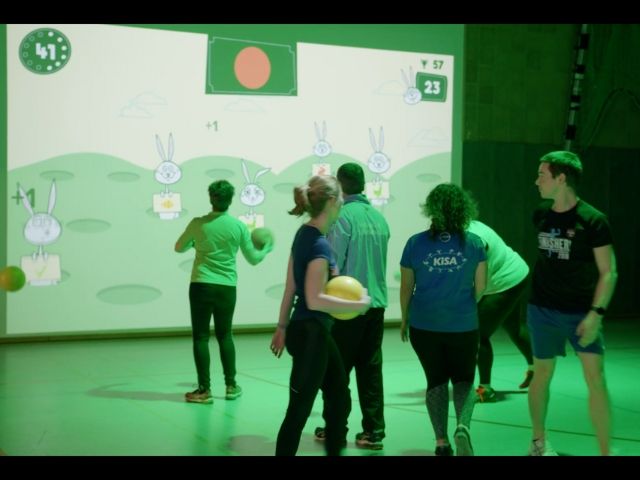 група възрастни играят на интерактивна игра пред голям екран - снимка 