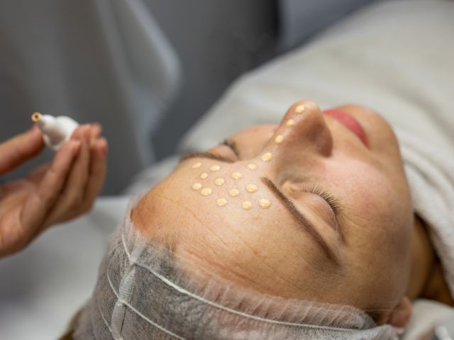 женско лице с нанесен цветен пигмент върху кожата, по време на козметична процедура
