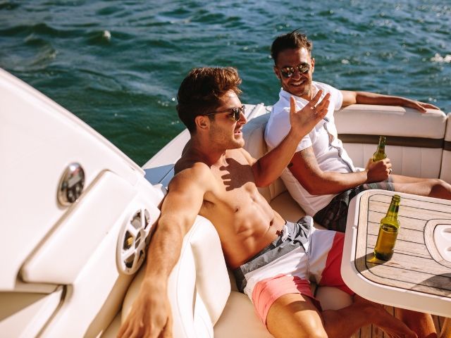двама мъже пият бира седнали на борда на яхта - снимка