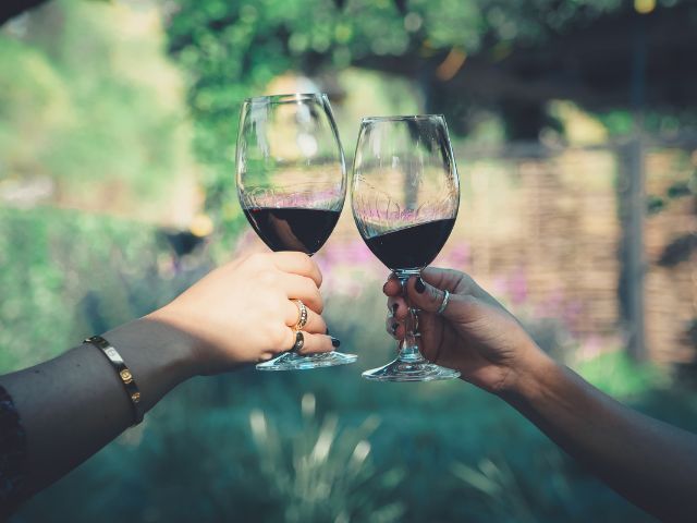 две ръце държат чаши с червено вино